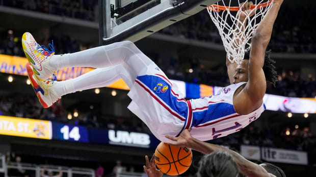 Dec 30, 2023; Kansas City, Missouri, USA; Kansas Jayhawks guard Elmarko Jackson (13) dunks against Wichita State Shockers center Quincy Ballard (15) and guard Bijan Cortes (55) during the first half at T-Mobile Center. 